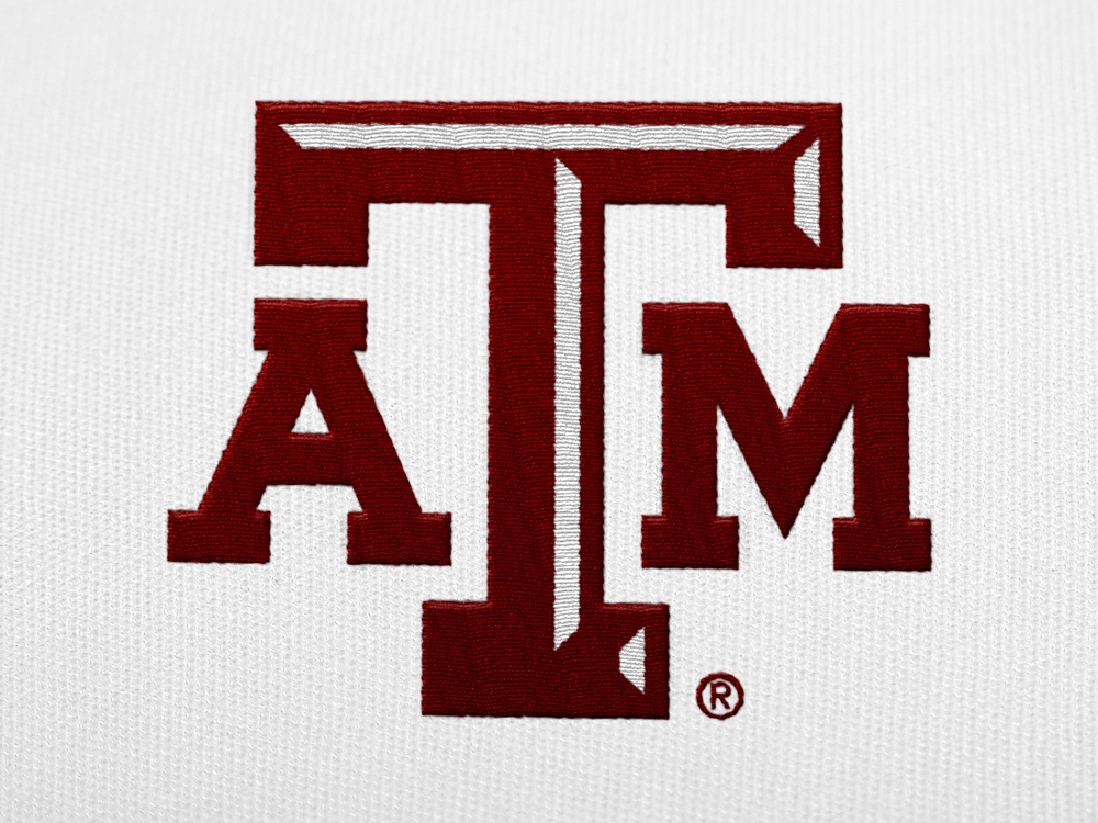 A maroon A&amp;M logo embroidered on a white shirt